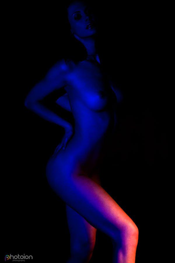 Nude posing in standing position with blue and orange lighting 