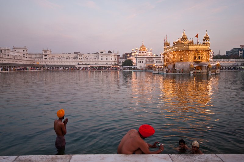 GETTING UP EARLY. This photograph was shot at The Golden Temple in India. I arrived early in the morning to capture a lovely light and two rituals happening simultaneously during morning bathing. One man prays while another photographs his smiling children.
