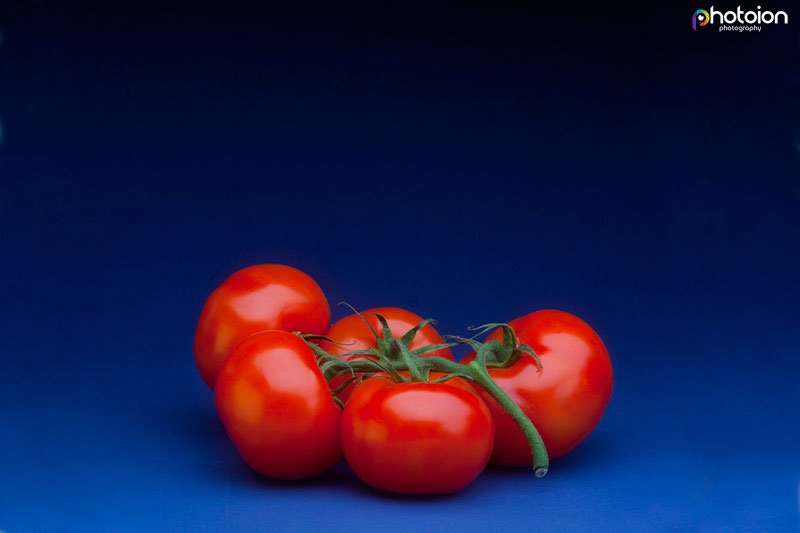 a picture of five tomatoes on a blue background